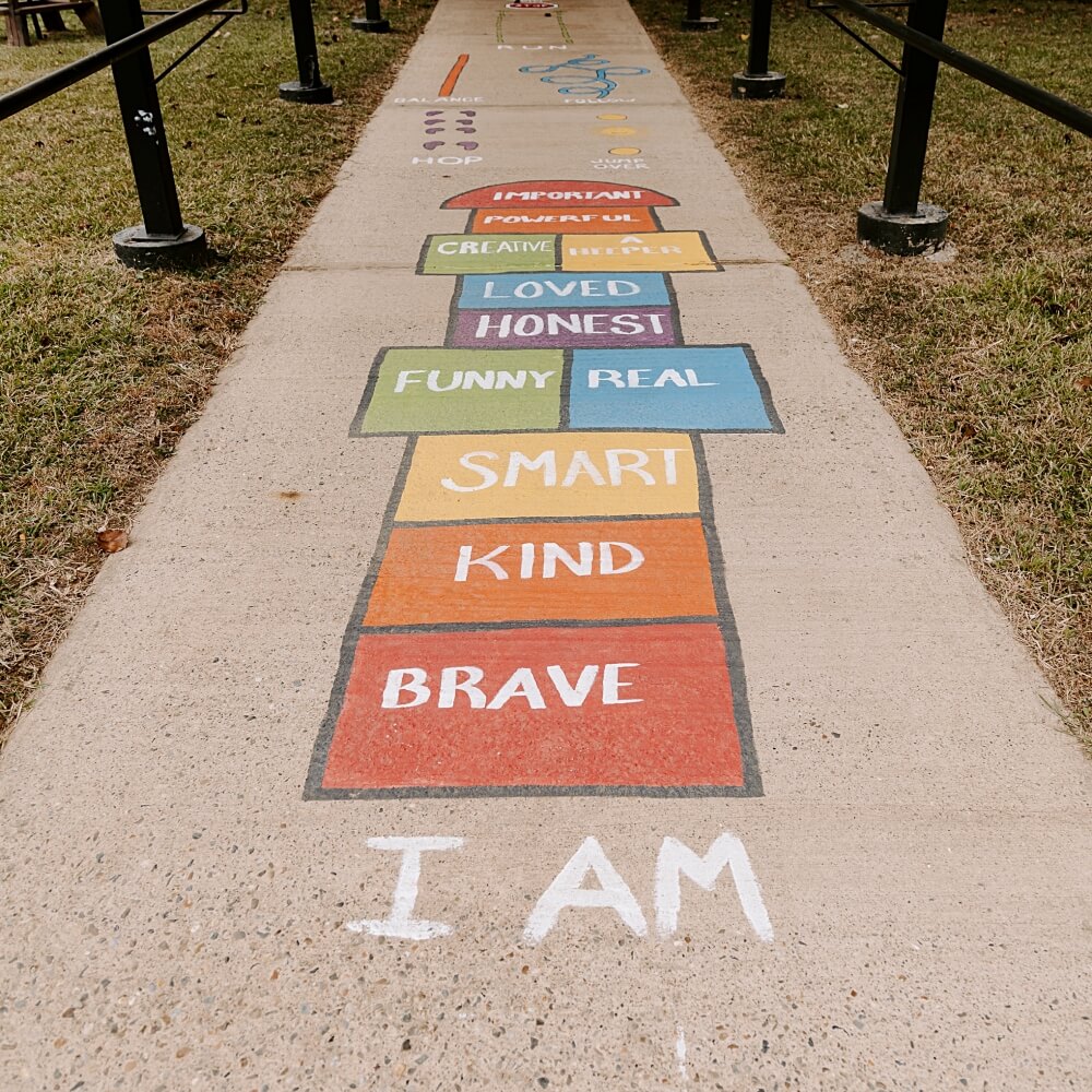 A colorful hopscotch path with affirmations like 'smart' and 'brave,' promoting positive self-esteem in children.