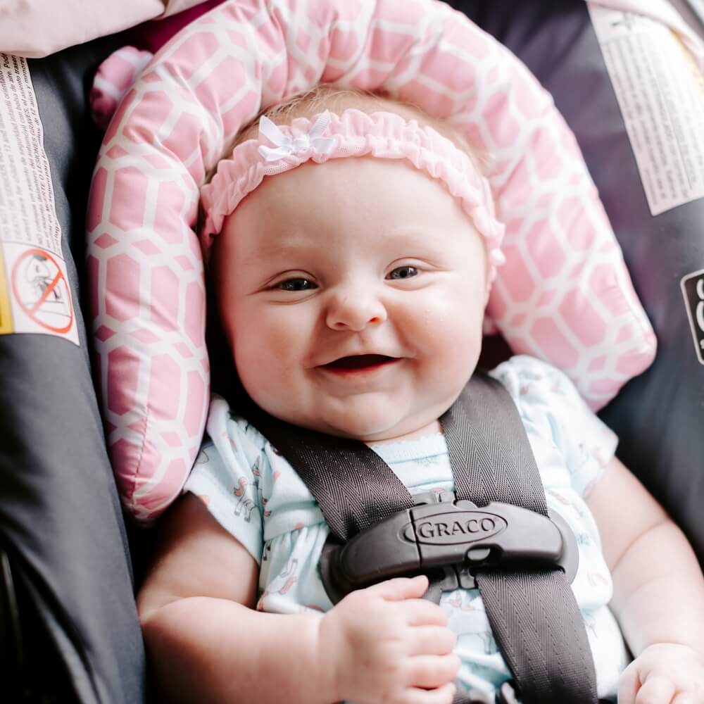A smiling baby comfortably seated in a car seat, highlighting safe and nurturing environments for infants.