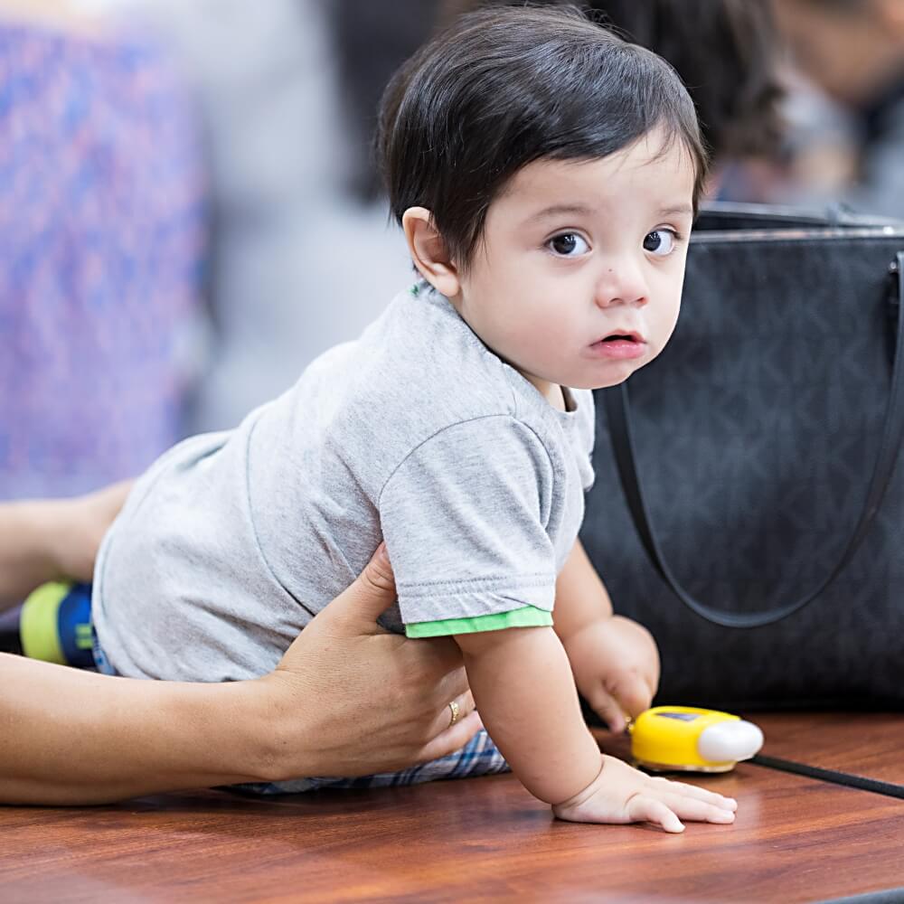 A toddler doing tummy time while being supported by an adult, showcasing early developmental support.