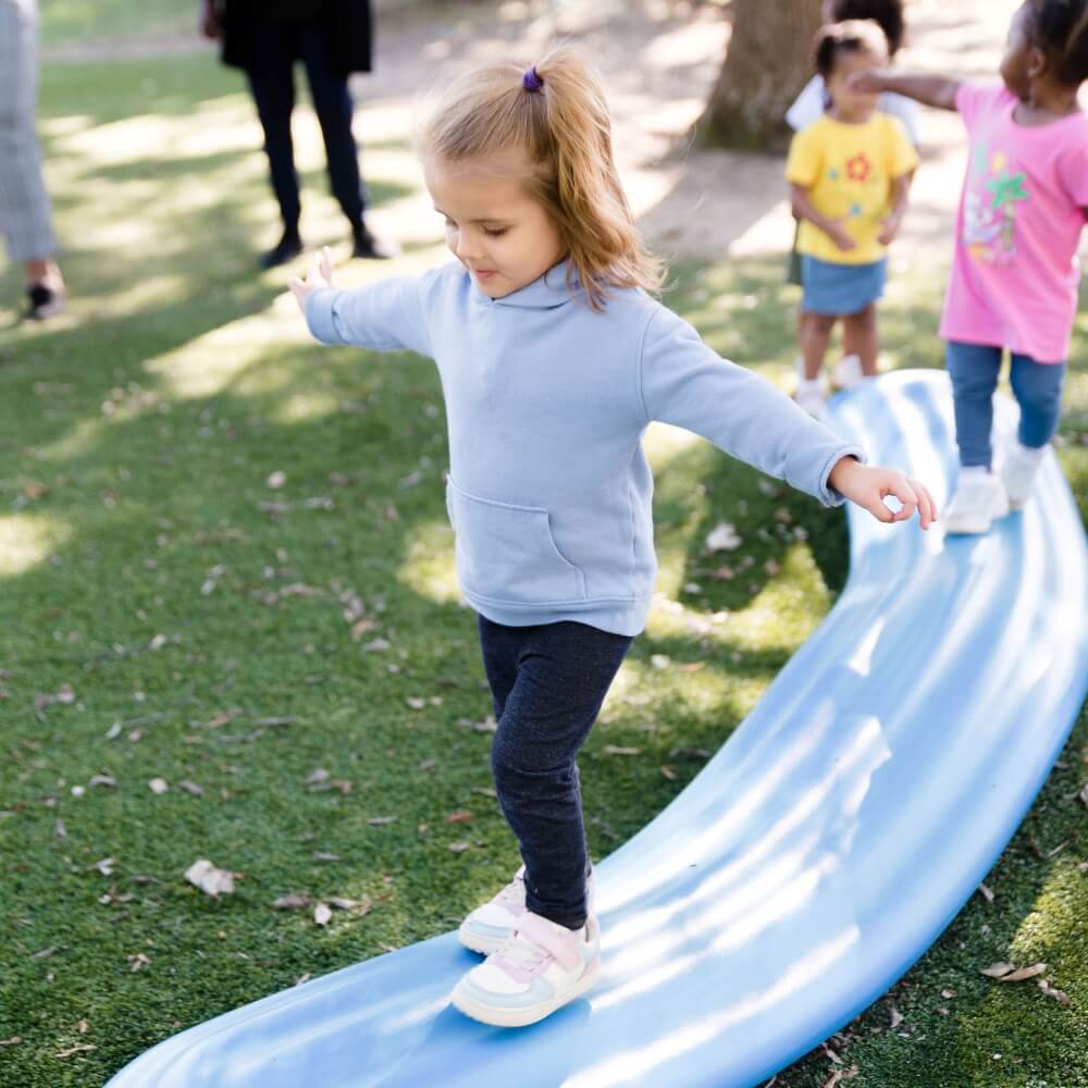 Child balancing on a play structure, developing motor skills through play.