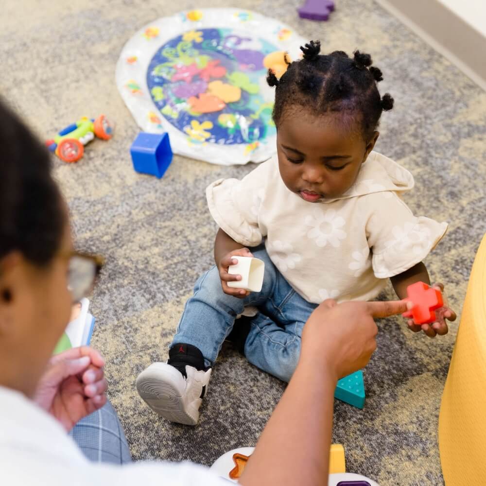 A child learning shapes with a teacher, highlighting interactive early education.