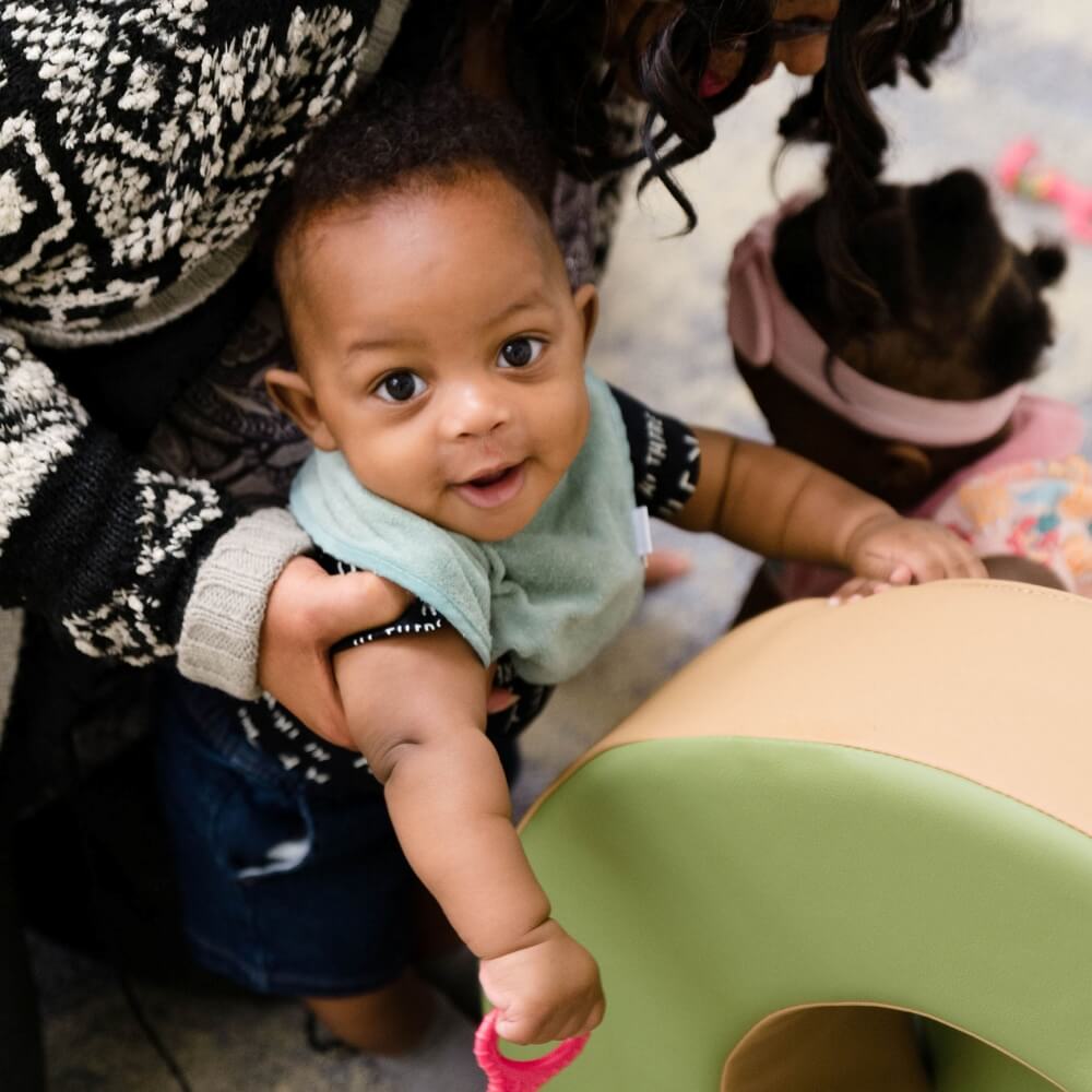 Teacher interacting with an infant during playtime, promoting early development.