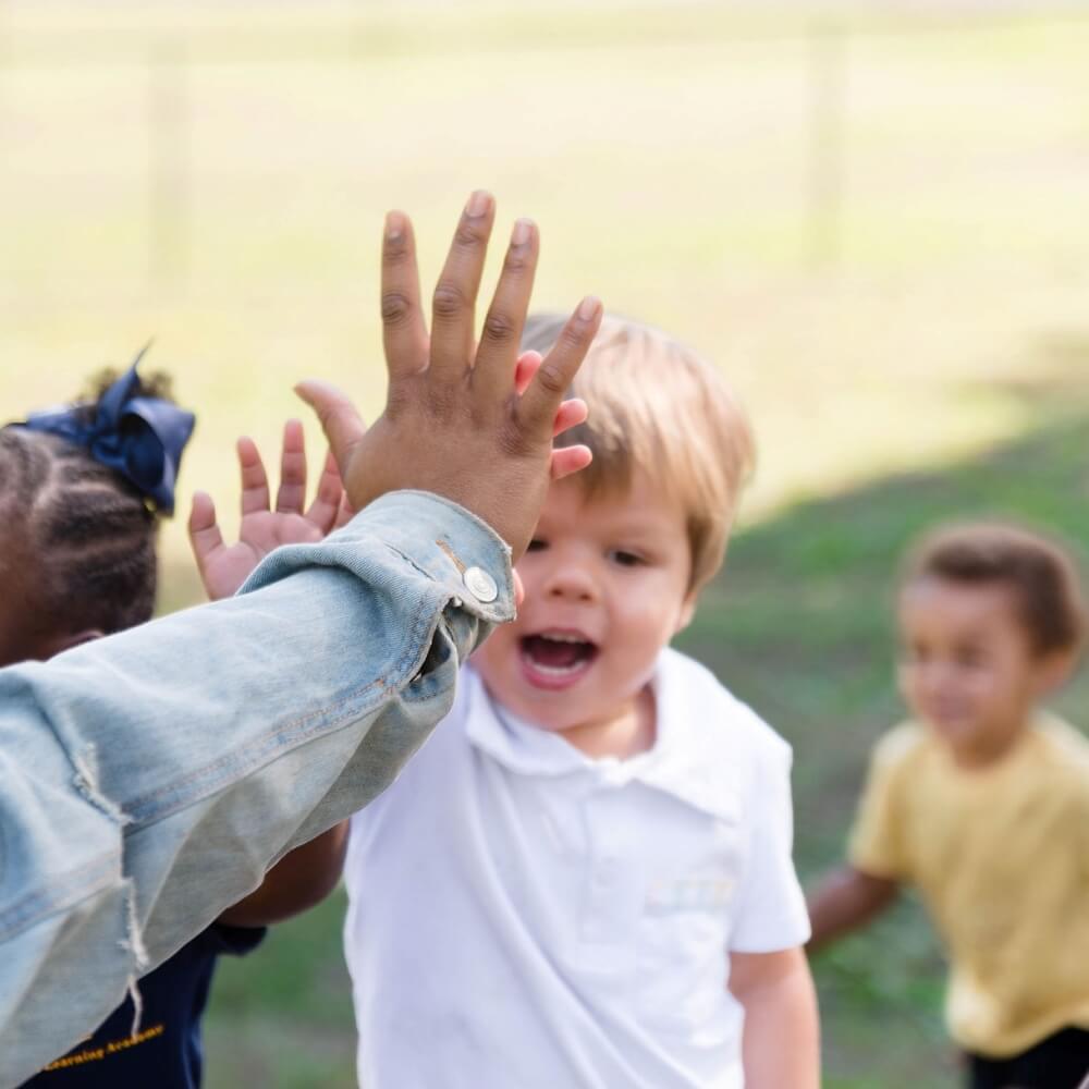 Teacher giving a high-five to a child, celebrating achievements in learning.